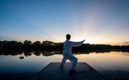 An Asian woman practises tai chi by the lake